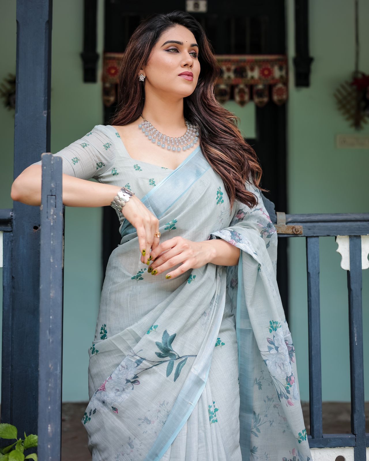 Light pastel blue linen saree with floral print, tassels on the edges, and an attached matching blouse piece.